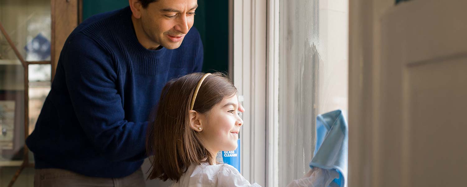 A man and child using Better Life's Window Cleaning to clean a window