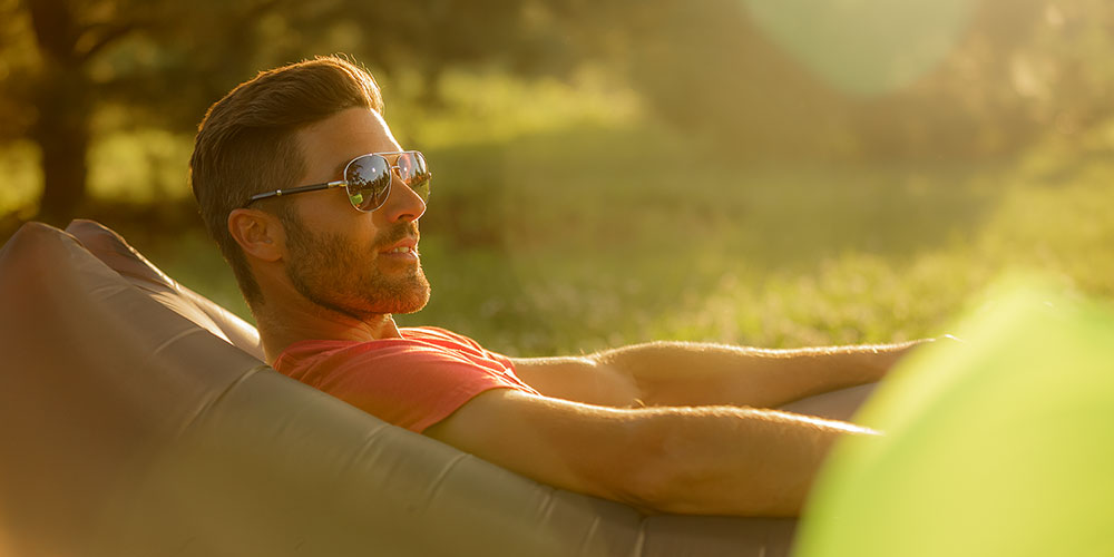 An image of a man relaxing on a Comfy Sack's Nomad Lounger during the setting of the sun
