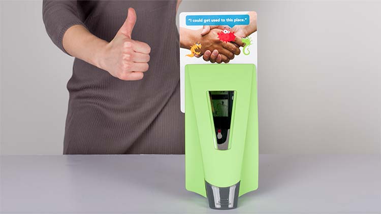 A person giving a thumbs up after successfully placing a placard behind a green symmetry dispenser